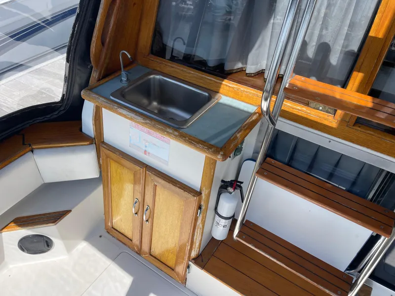 Slide: The Image of 1989 Bayliner 3288 boat interior with sink, wooden cabinets, and stairs. - 6