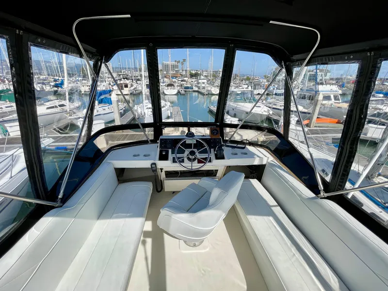 Slide: The Image of 1989 Bayliner 3288 boat interior with steering wheel, marina view, and white seating. - 8