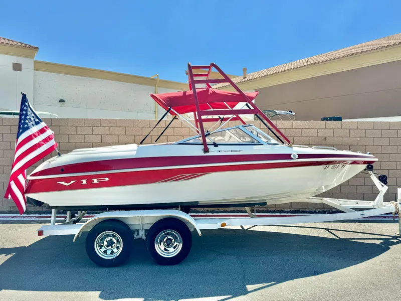 Slide: The Image of 1998 VIP Vixen boat on trailer with American flag, red and white design, sunny day. - 1