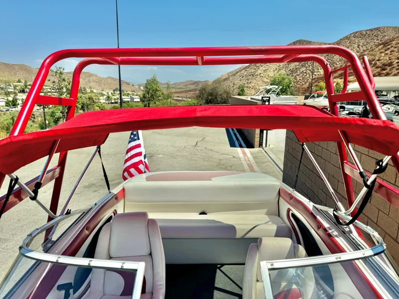 Slide: The Image of 1998 VIP Vixen boat with red canopy and American flag, parked near scenic hills. - 17