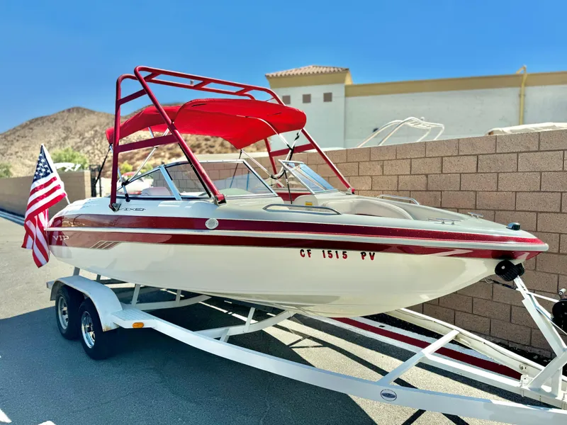 Slide: The Image of 1998 VIP Vixen boat with red canopy on trailer, American flag displayed. - 2