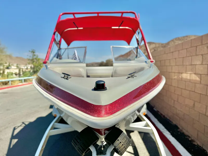 Slide: The Image of 1998 VIP Vixen boat with red canopy on trailer, parked near brick wall. - 3