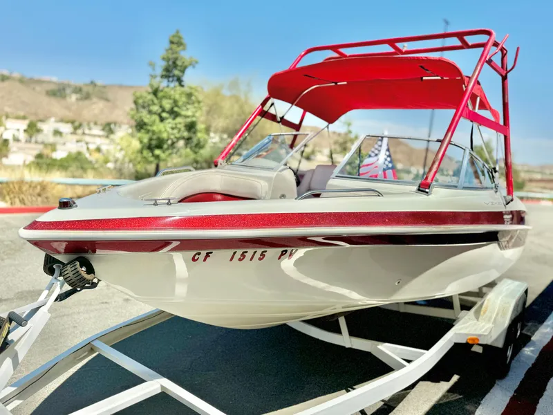Slide: The Image of 1998 VIP Vixen boat with red canopy on trailer, parked outdoors. - 4