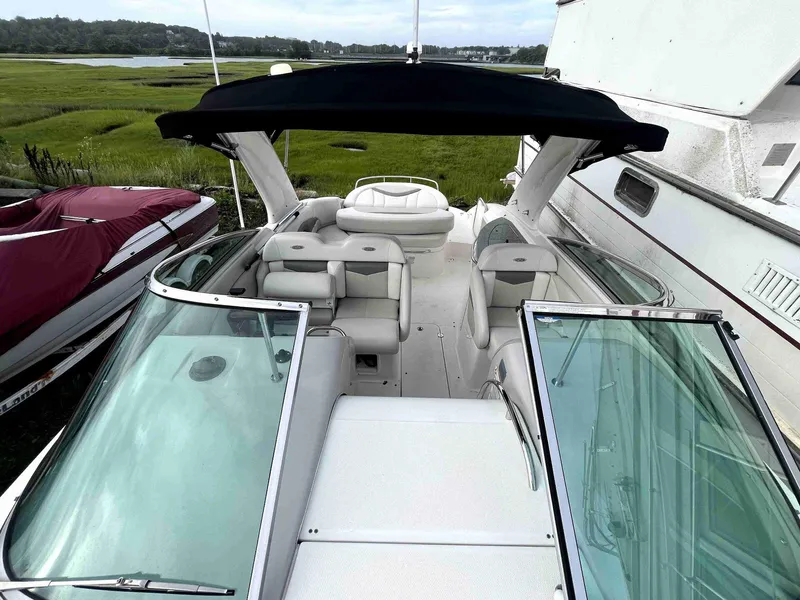 Slide: The Image of 2007 Chaparral 275 SSi boat with open deck and black canopy, docked near grassy shoreline. - 26