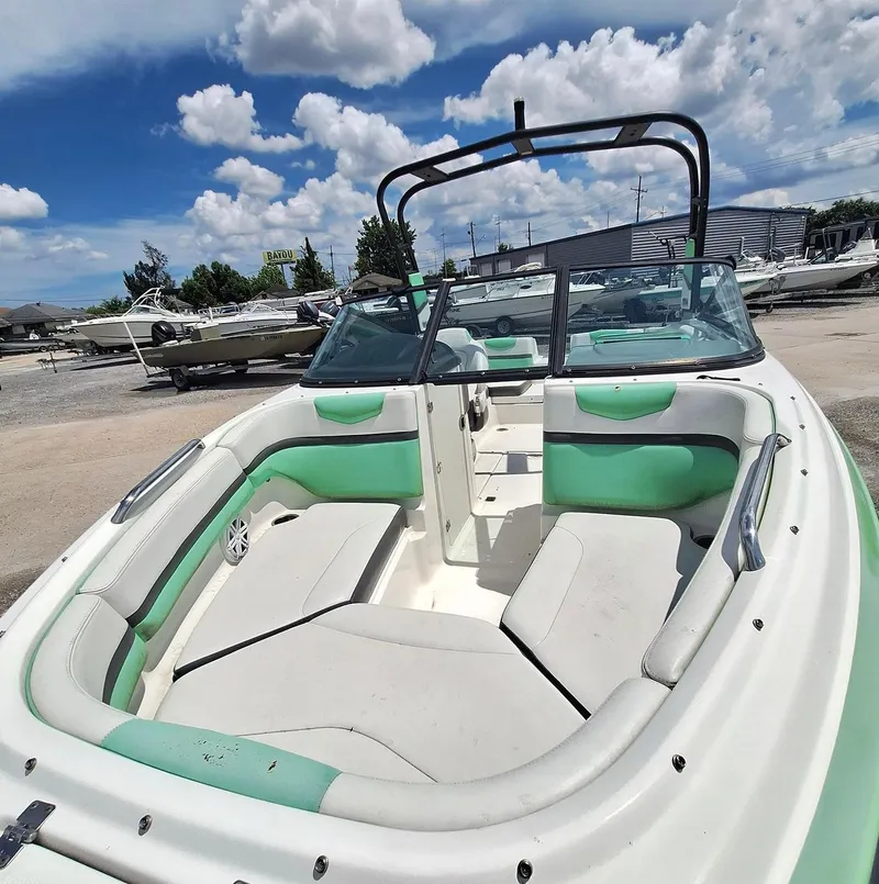 Slide: The Image of 2016 Chaparral Vector 203 boat with green and white seating, parked under a blue sky. - 13