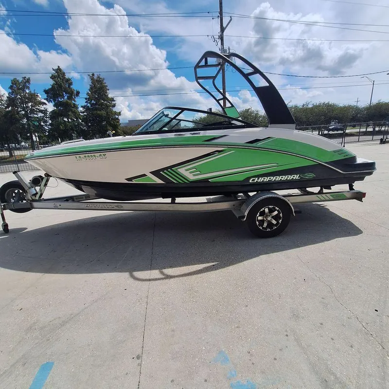 Slide: The Image of 2016 Chaparral Vector 203 boat with green accents on a trailer, parked outdoors. - 2