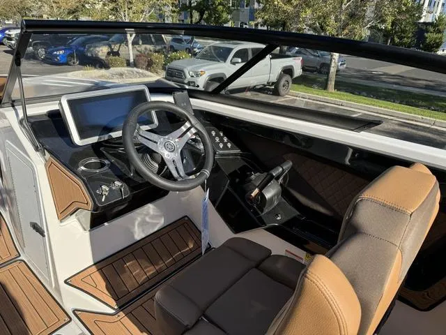 Slide: The Image of 2024 Yamaha Boats 252S cockpit with modern steering and dashboard in a parking lot. - 8