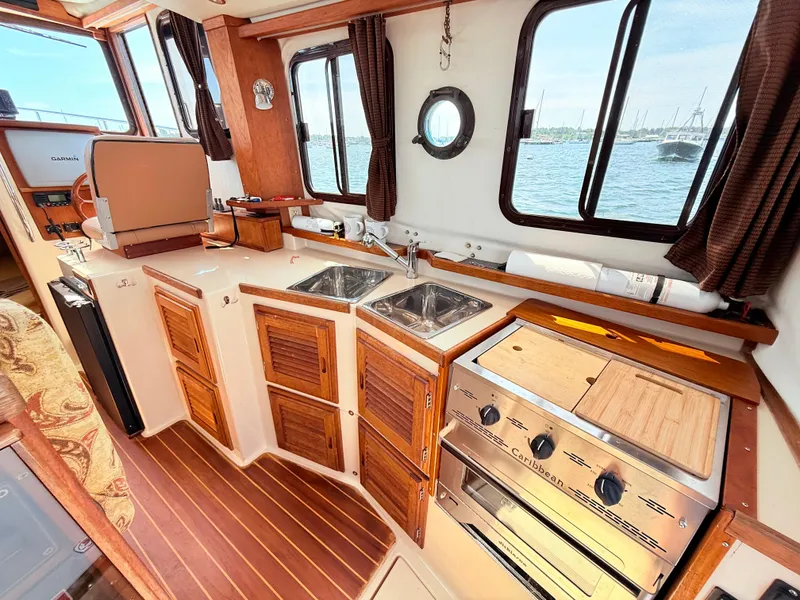 Slide: The Image of Cozy 2009 Ranger Tugs R-29 galley with wood accents, dual sinks, and ocean view. - 11