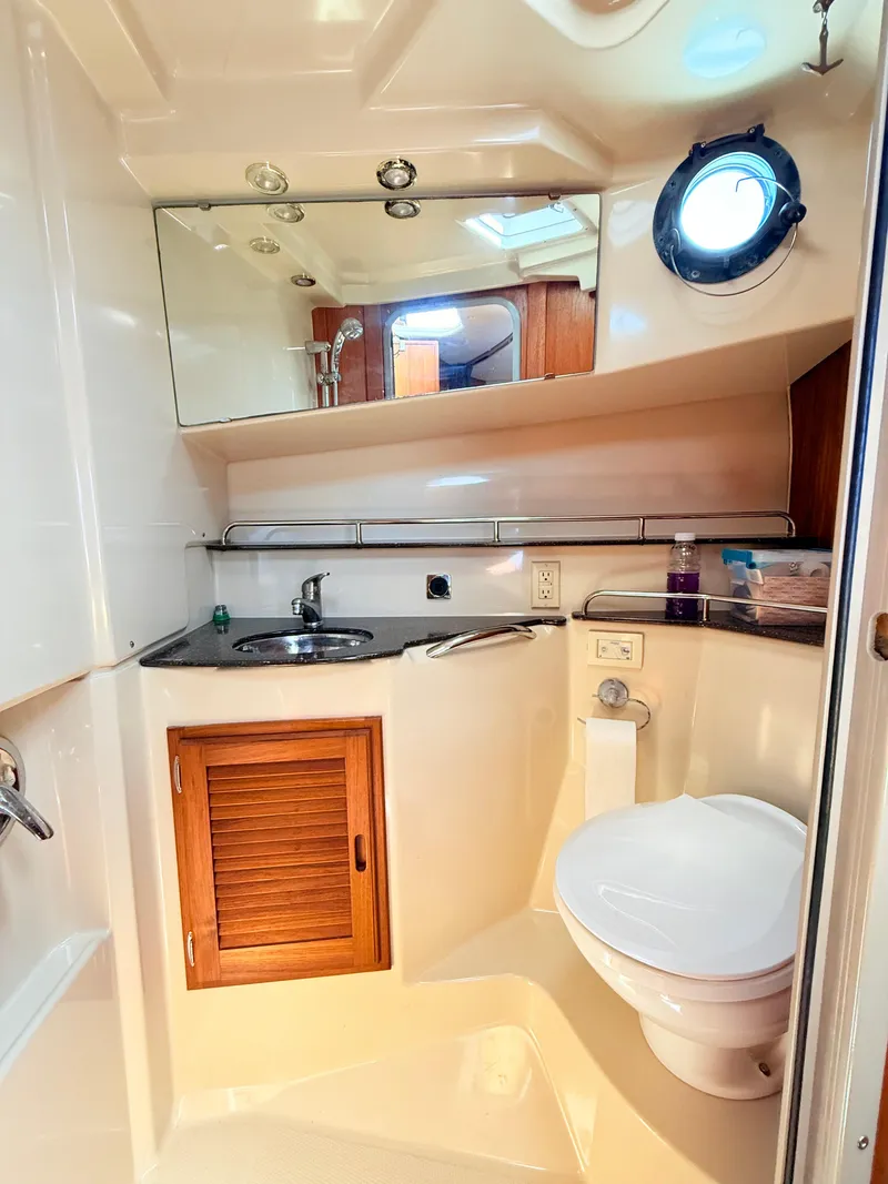 Slide: The Image of 2009 Ranger Tugs R-29 boat bathroom with sink, toilet, mirror, and porthole window. - 16