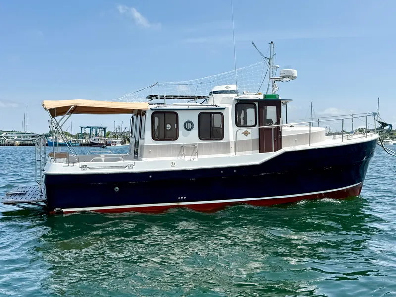 Slide: The Image of 2009 Ranger Tugs R-29 boat on water, featuring a blue hull and tan canopy. - 2
