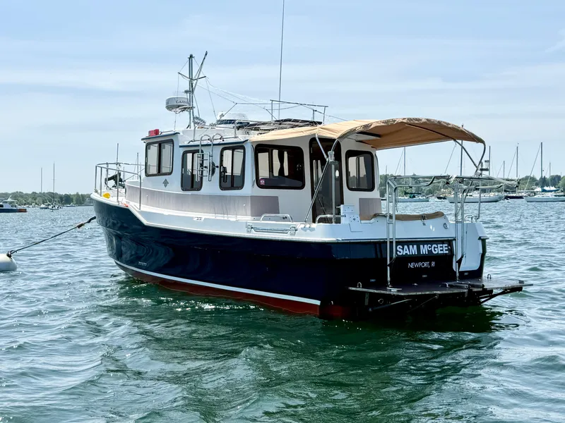 Slide: The Image of 2009 Ranger Tugs R-29 boat on water, featuring a canopy and moored in a scenic harbor. - 6