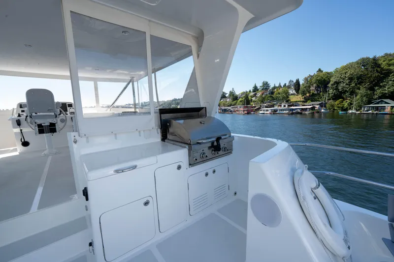 Slide: The Image of 2022 Outer Reef Yachts 720 Motoryacht with outdoor grill on deck, scenic waterfront view. - 22