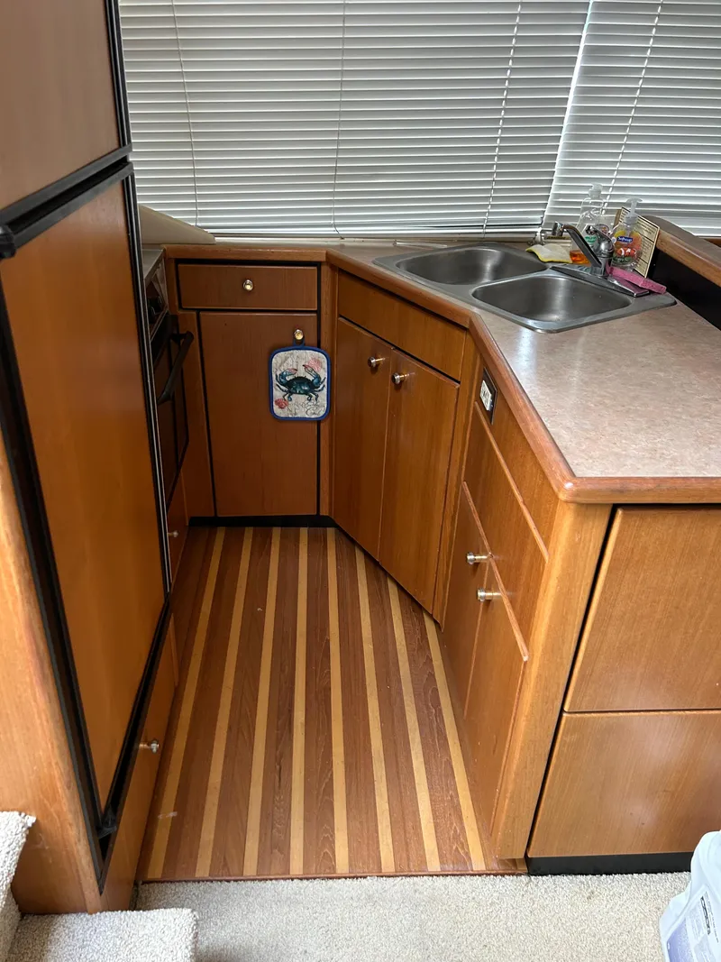 Slide: The Image of 2000 Bayliner 4087 Motoryacht kitchen with wood cabinets, dual sink, and striped flooring. - 14