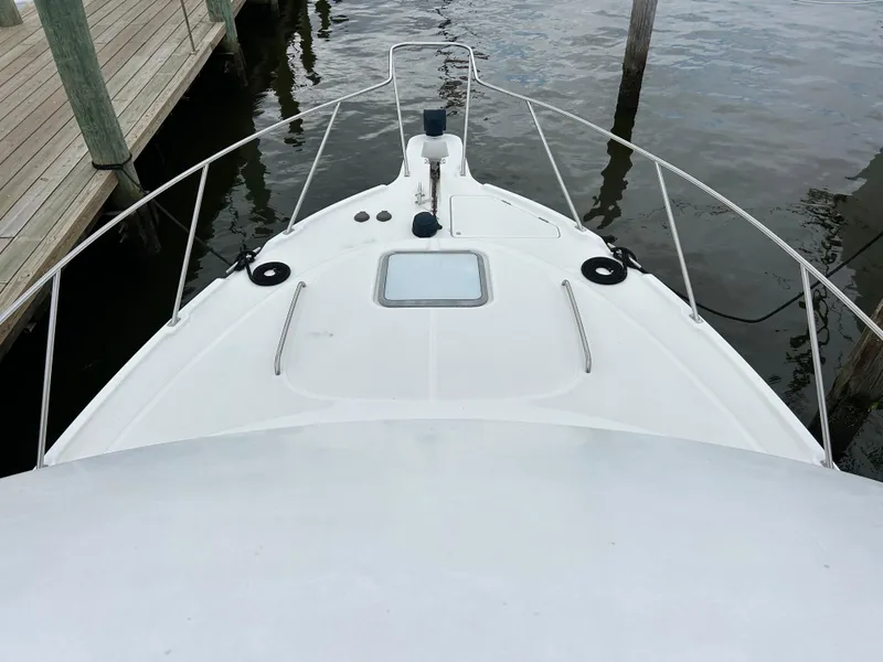 Slide: The Image of Bayliner 4087 Motoryacht 2000 bow view at dock, featuring sleek design and railing. - 4