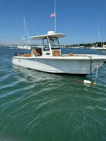 Slide: The Image of 2022 Sea Hunt Ultra 265 SE boat on water, clear sky, American flag. - 4