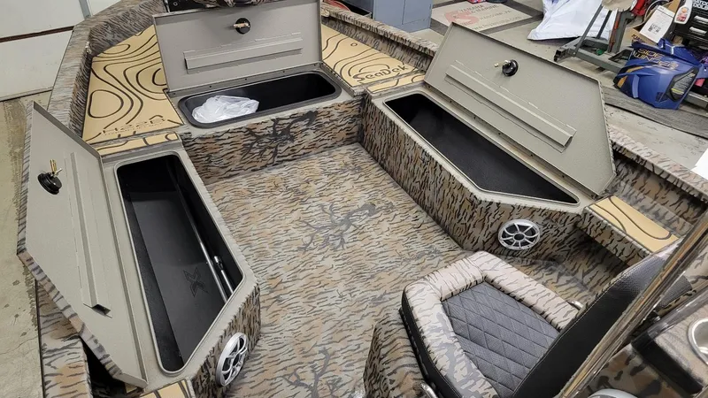 Slide: The Image of 2025 Xpress H22 Bay boat interior with open storage compartments and camo design. - 17