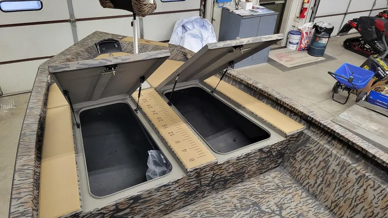 Slide: The Image of 2025 Xpress H210 Bay boat interior with open storage compartments in a garage. - 14