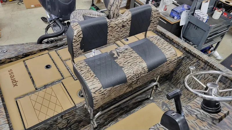 Slide: The Image of 2025 Xpress H210 Bay boat interior with camo seating and steering wheel. - 21