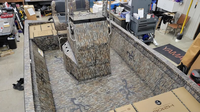 Slide: The Image of 2025 Xpress H210 Bay boat interior with camo design, in a workshop setting. - 7