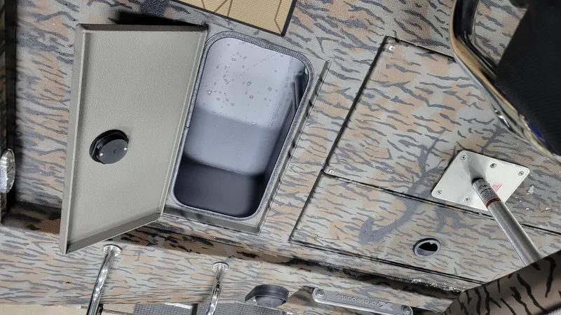 Slide: The Image of 2025 Xpress H210 Bay boat interior with storage compartment and camo design. - 12