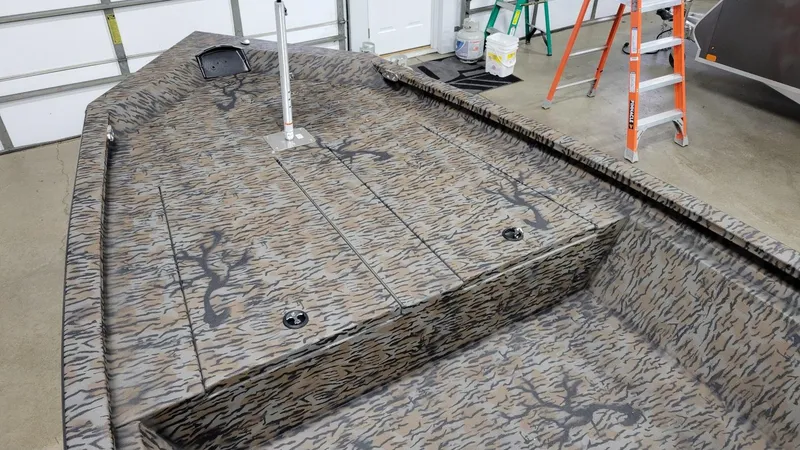 Slide: The Image of 2025 Xpress H210 Bay boat interior with camouflage pattern, in a garage setting. - 7