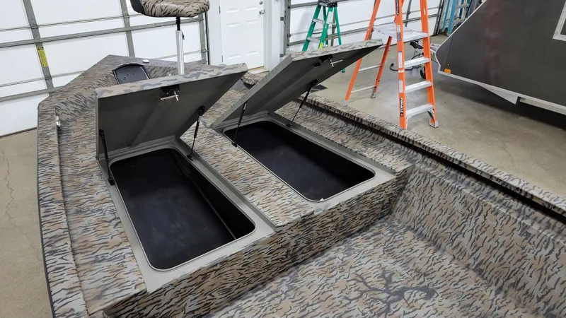 Slide: The Image of 2025 Xpress H210 Bay boat with open storage compartments in a garage setting. - 8