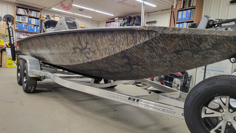 Slide: The Image of 2025 Xpress X19 Pro Bass boat with Yamaha Vmax 200, camo design, on trailer in garage. - 10