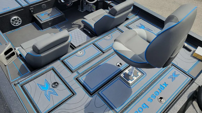 Slide: The Image of 2025 Xpress X21 Pro Bass boat interior with gray and blue seating and storage compartments. - 13