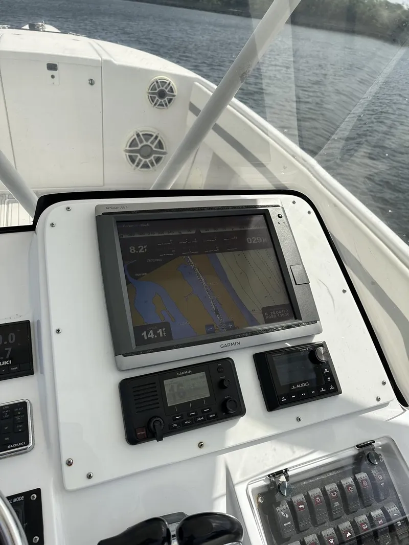 Slide: The Image of 2003 Intrepid 32 boat dashboard with navigation system and controls on a calm water backdrop. - 12