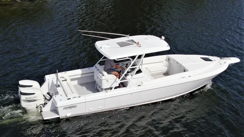 Slide: The Image of 2003 Intrepid 32 boat cruising on water, featuring a sleek white design and Suzuki outboard engine. - 7