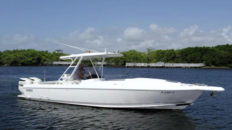 Slide: The Image of 2003 Intrepid 32 boat cruising on a calm river under a clear blue sky. - 3