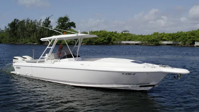 Slide: The Image of 2003 Intrepid 32 boat cruising on a calm river with lush green shoreline. - 34