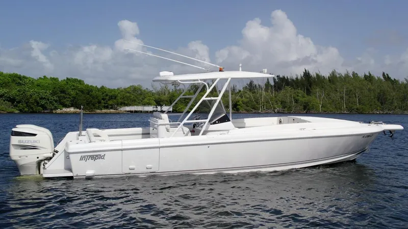 Slide: The Image of 2003 Intrepid 32 boat on water, white hull, outboard motor, clear sky, lush greenery background. - 35
