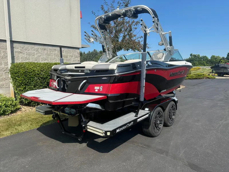 Slide: The Image of 2017 MasterCraft XT20 boat on trailer, red and black, parked outdoors. - 4