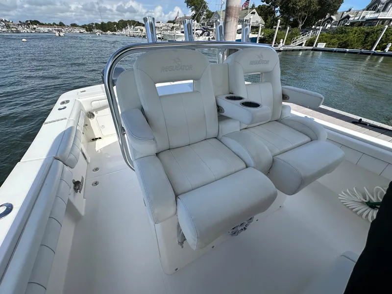 Slide: The Image of 2017 Regulator 31 boat with white cushioned seating and cup holders, docked by the water. - 20
