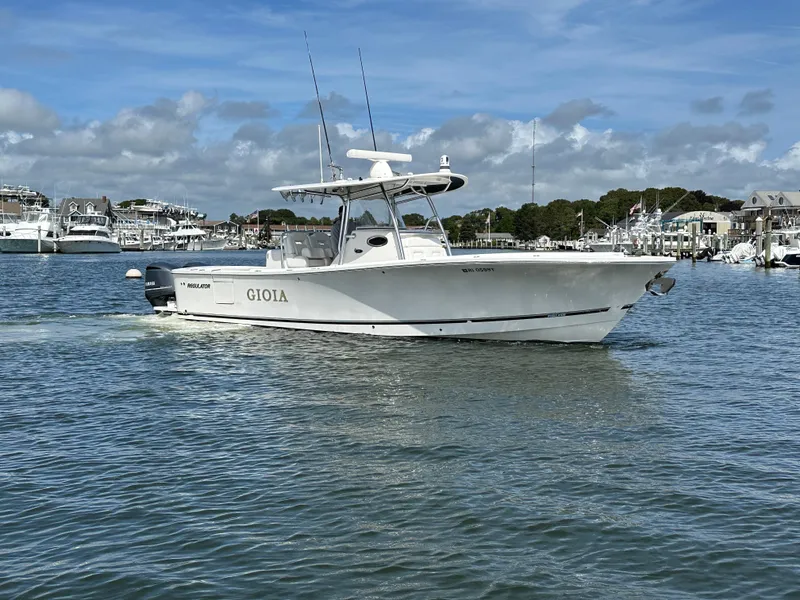 Slide: The Image of 2017 Regulator 31 boat cruising in a marina under a partly cloudy sky. - 3