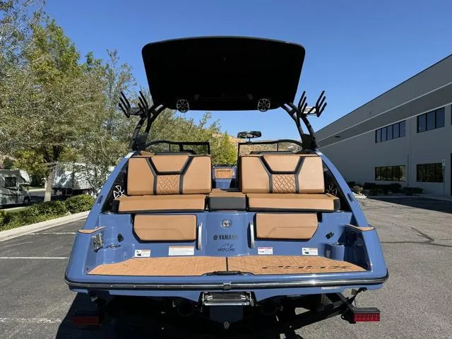 Slide: The Image of 2024 Yamaha Boats 255XD, rear view, blue exterior, tan seating, parked outdoors. - 5