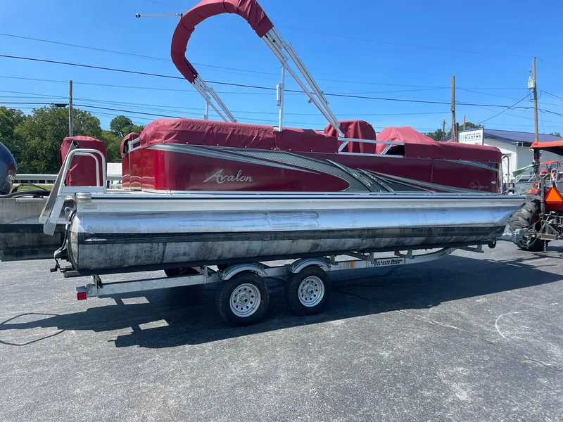 Slide: The Image of 2021 Avalon GS Cruise 23' pontoon boat on trailer, red canopy, parked outdoors. - 7
