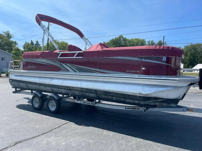 Slide: The Image of 2021 Avalon GS Cruise 23' pontoon boat on trailer, red canopy, parked outdoors. - 8