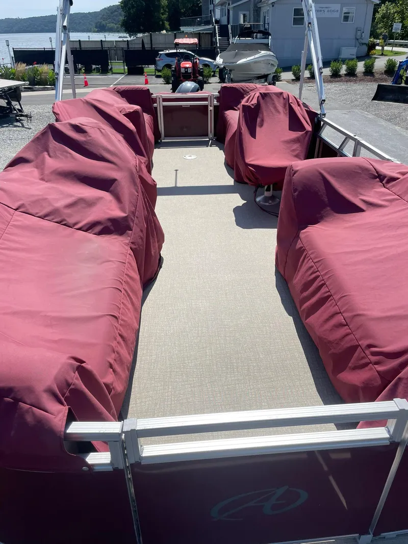 Slide: The Image of 2021 Avalon GS Cruise 23' pontoon boat with red covers, docked near a lake. - 9