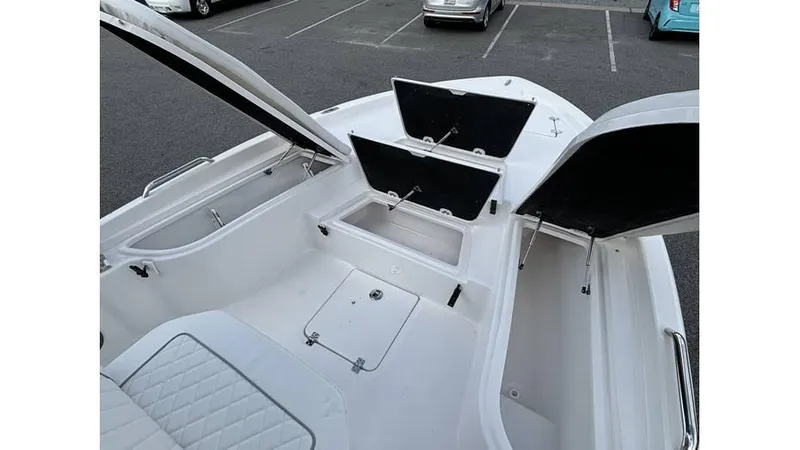 Slide: The Image of 2025 Sea Fox 251 Bay Fox boat with open storage compartments in a parking lot. - 11