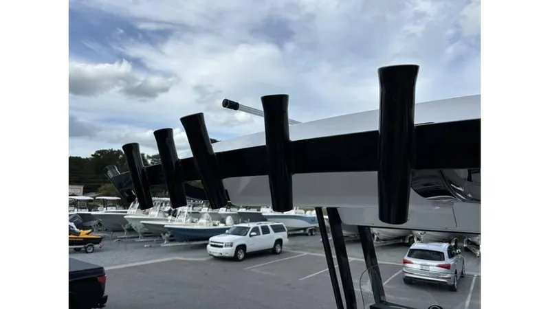 Slide: The Image of 2025 Sea Fox 251 Bay Fox boat with rod holders, parked in a marina with other vehicles. - 13