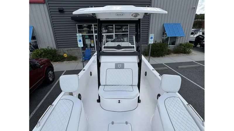 Slide: The Image of 2025 Sea Fox 251 Bay Fox boat with white seating and center console, parked outside a building. - 5
