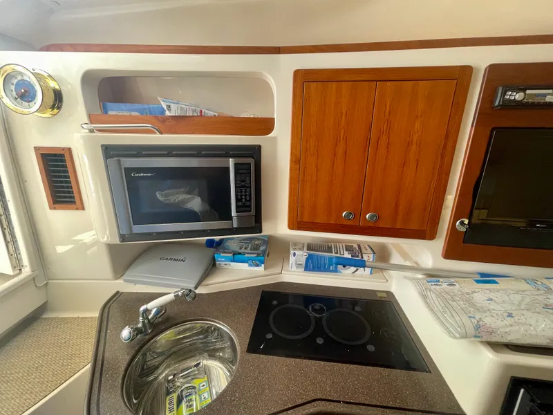 Slide: The Image of 2009 Grady-White 330 Explorer boat interior with microwave, sink, and wooden cabinets. - 6