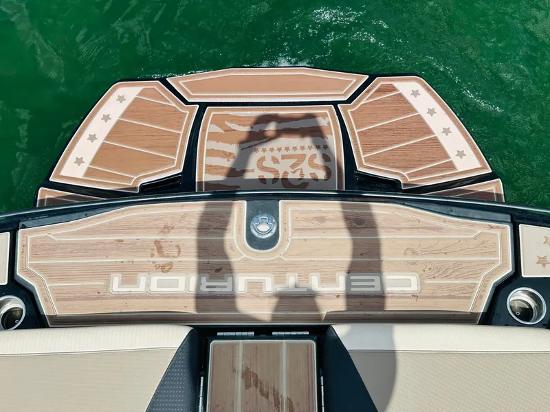Slide: The Image of Centurion Ri245 boat deck with wood finish, shadow, and green water background. - 10