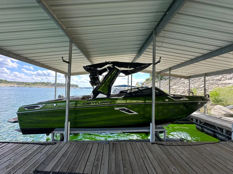 Slide: The Image of 2021 Centurion Ri245 boat in dock, vibrant green color, under covered shelter. - 17