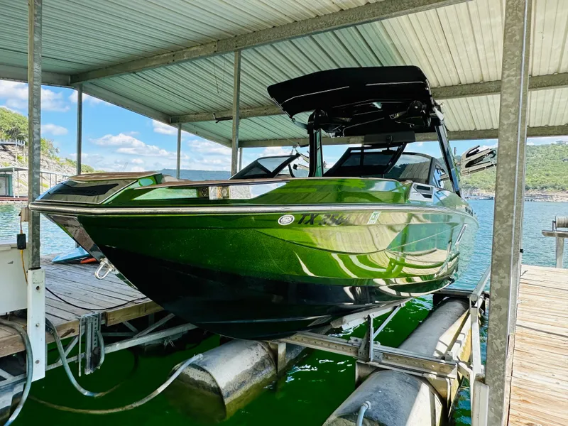 Slide: The Image of 2021 Centurion Ri245 boat in green, docked under a covered marina. - 18