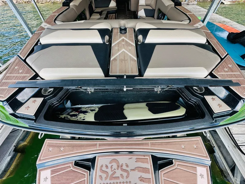 Slide: The Image of 2021 Centurion Ri245 boat with open storage compartment, featuring sleek seating and wood accents. - 27