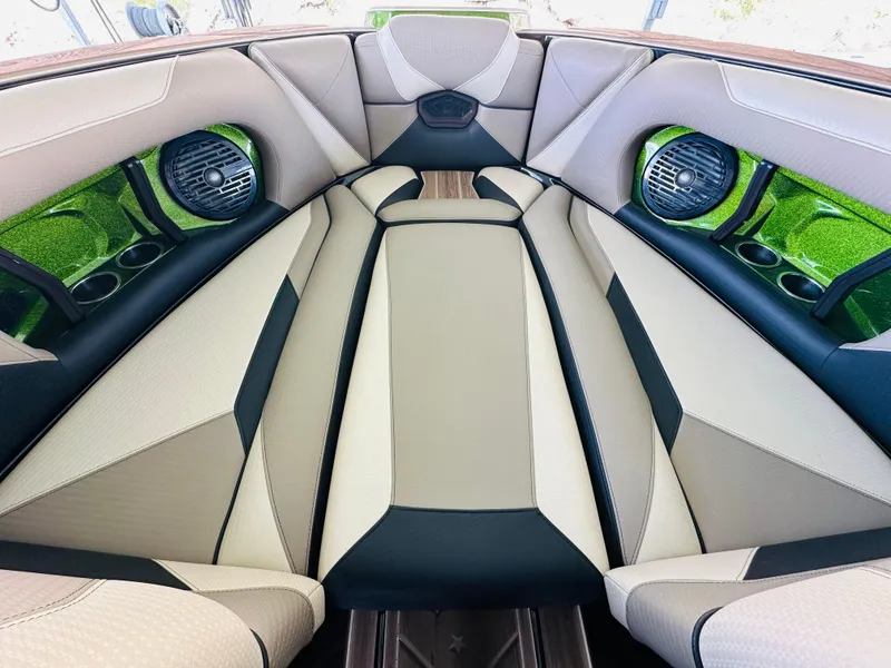 Slide: The Image of 2021 Centurion Ri245 boat interior with beige and black seating, green accents, and speakers. - 36