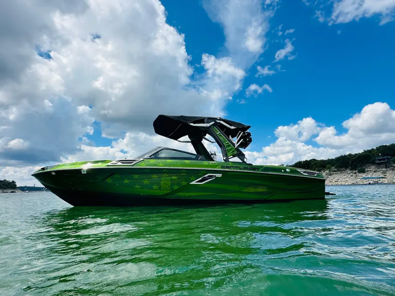 Slide: The Image of 2021 Centurion Ri245 boat on a lake under a blue sky with clouds. - 7